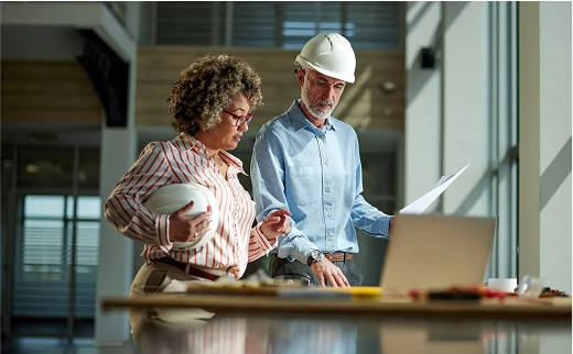 Two architects reviewing plans in front of a computer, representing the integration of smart access control into building design