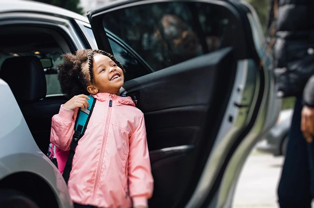 Child stepping out of a car, representing safe and controlled access during school drop-off through smart entry systems